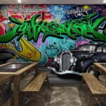 Fototapeten Schwarzes Auto mit Rädern vor einer bunten Wand