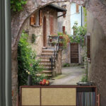 Fototapeten Charmante steinerne Gasse mit Torbogen